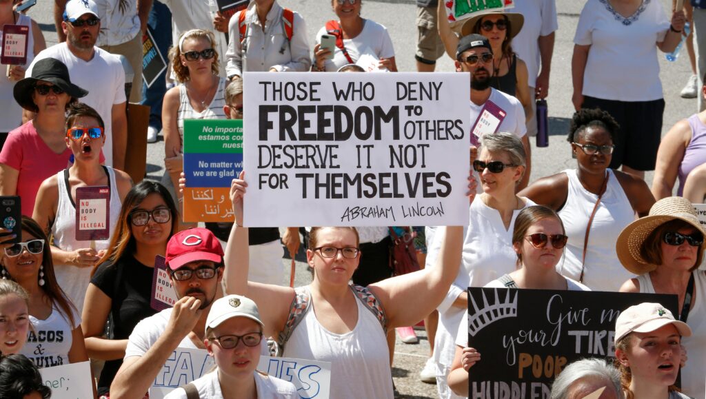 A large group of diverse individuals protesting, holding signs advocating for freedom and justice.